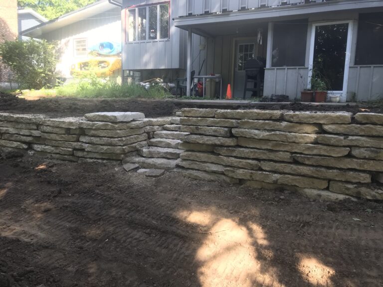 Newly constructed natural stone retaining wall in backyard.